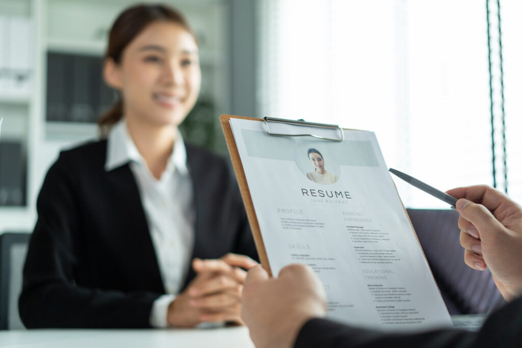 A job applicant being interviewed by the hiring manager while reviewing her resume.