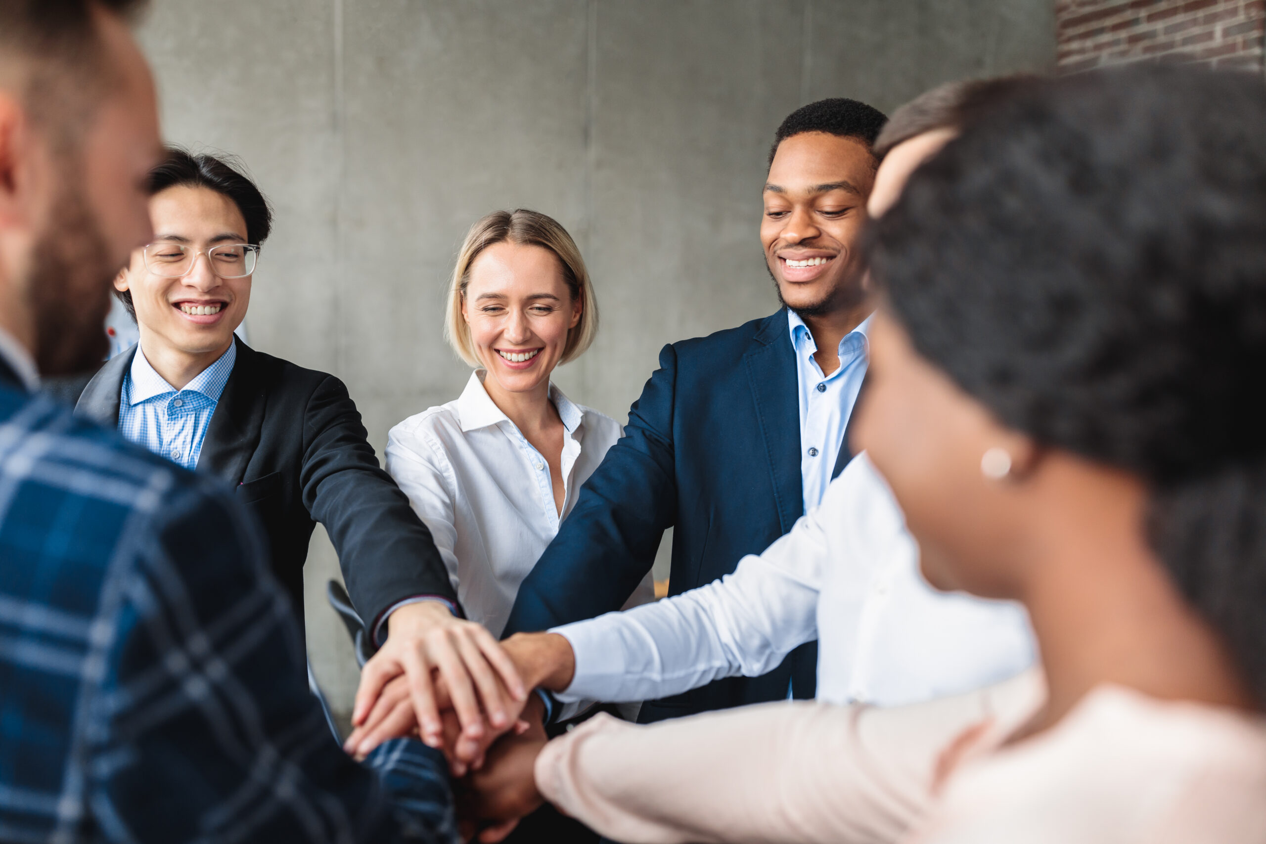 A multiracial group of young professionals joining hands to showcase teamwork.